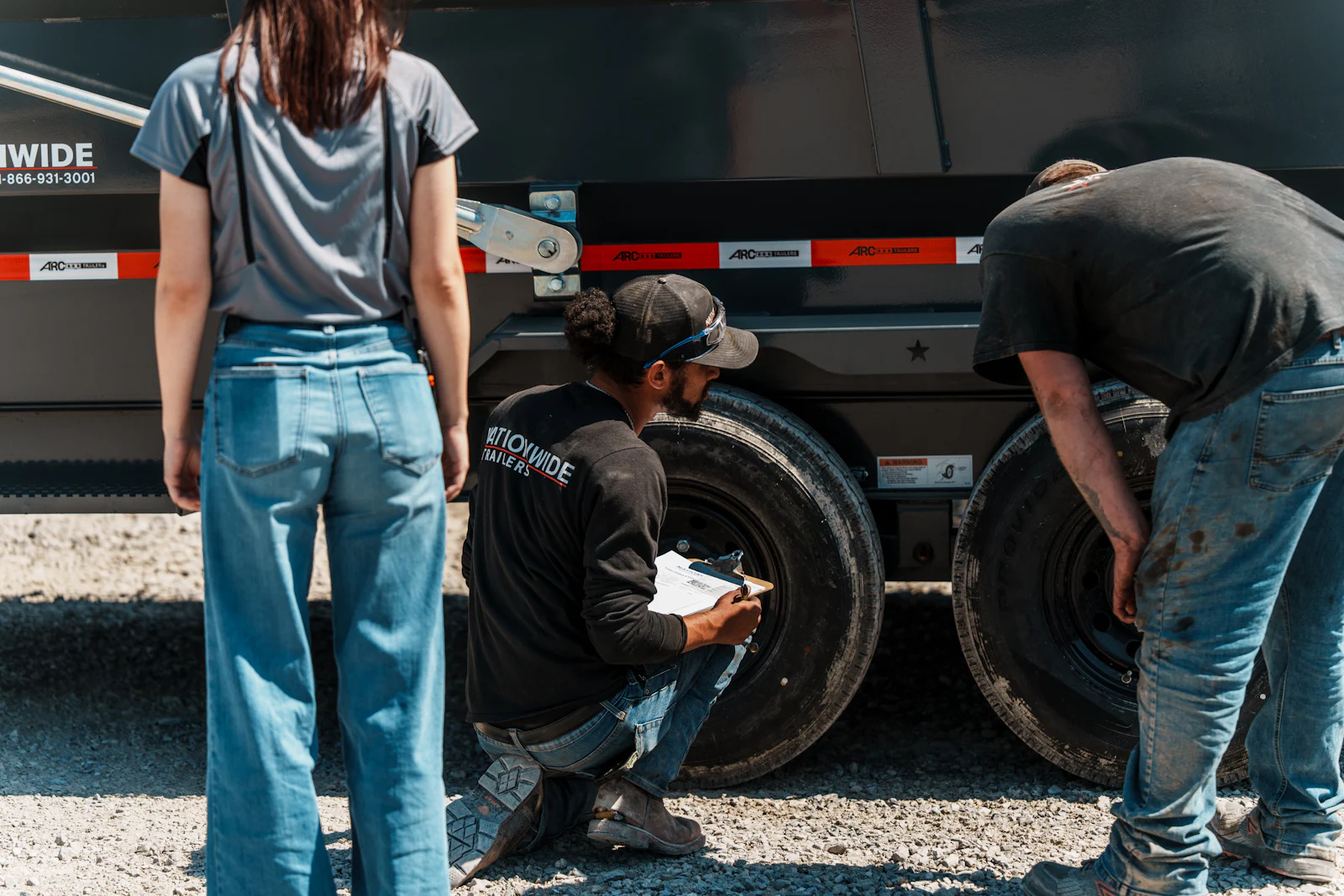 Technician inspecting a dump trailer with customers
