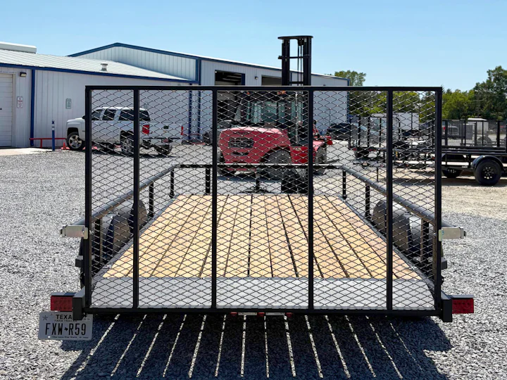 Rear view of the black Karavan utility trailer showing the full-width mesh ramp gate and wood deck.